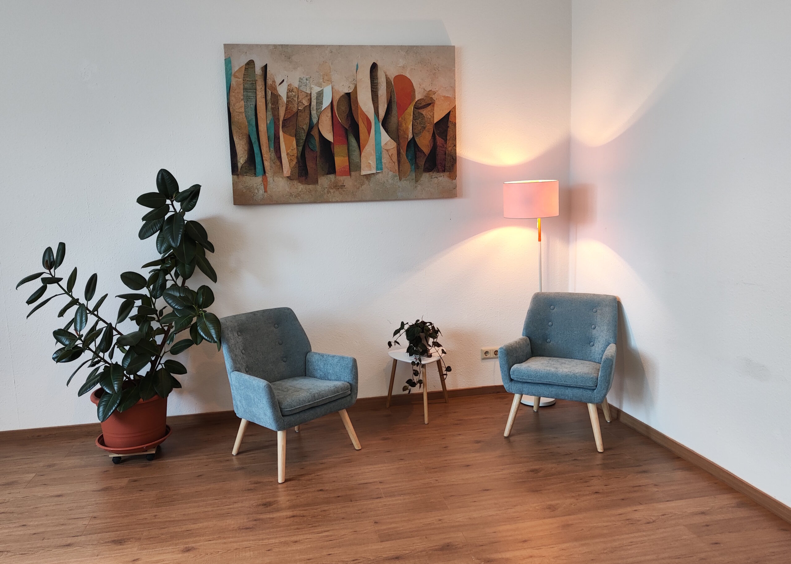 Zwei gemütliche Stühle stehen in einer Ecke mit Licht, einem Bild und einer Pflanze.